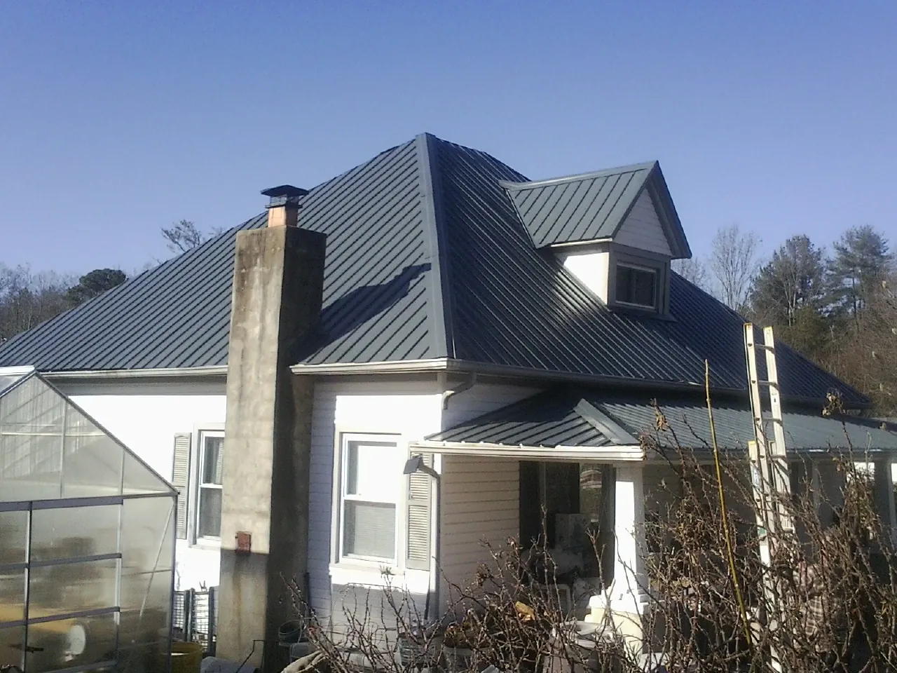 Dark blue standing seam metal roof on a white farmhouse with dormer — Slate & Tile Roof Repair by Roofing Brothers in Rising Sun