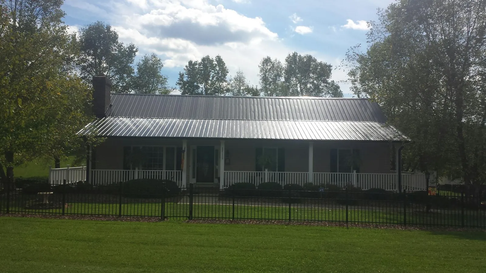 Gray metal roof on a brick ranch with a full width front porch — Gutter Guard Installation work by our crew in Rising Sun