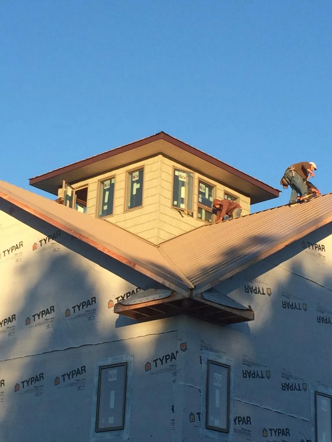 Roofers working around a rooftop cupola on a new metal roof at sunset — Roof Waterproofing in Rising Sun by Roofing Brothers